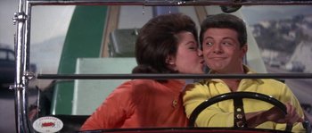 Movie still from “Muscle Beach Party” (1964), directed by William Asher – A man and a woman kissing in a car mirror; Medium shot, Low angle