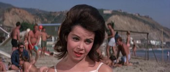 Movie still from “Muscle Beach Party” (1964), directed by William Asher – A woman with a big hair do standing on a beach; Close Up shot, Low angle