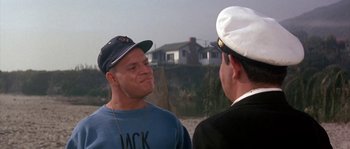 Movie still from “Muscle Beach Party” (1964), directed by William Asher – Two men talking to each other on the beach; Medium shot, Over the shoulder angle