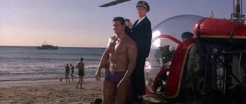 Movie still from “Muscle Beach Party” (1964), directed by William Asher – A man is getting his hair cut on the beach; Wide shot, Low angle
