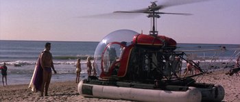 Movie still from “Muscle Beach Party” (1964), directed by William Asher – A red and white helicopter on a beach with people standing around; Extreme Wide shot, Low angle