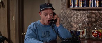 Movie still from “Muscle Beach Party” (1964), directed by William Asher – A man talking on a phone while sitting at a table; Medium shot, High angle
