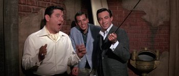 Movie still from “Muscle Beach Party” (1964), directed by William Asher – A group of men standing next to each other in a room; Medium shot, Low angle