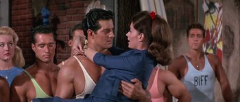 Movie still from “Muscle Beach Party” (1964), directed by William Asher – A man and a woman hugging each other in front of a brick wall; Medium shot, Over the shoulder angle