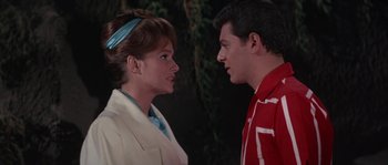 Movie still from “Muscle Beach Party” (1964), directed by William Asher – A man and a woman standing next to each other in front of a tree; Close Up shot, Low angle