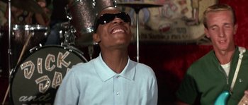 Movie still from “Muscle Beach Party” (1964), directed by William Asher – A young man wearing sunglasses and a white shirt; Close Up shot, Low angle