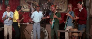 Movie still from “Muscle Beach Party” (1964), directed by William Asher – Two men are singing in front of a band; Medium shot, Low angle