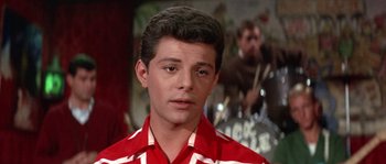 Movie still from “Muscle Beach Party” (1964), directed by William Asher – A man in a red and white striped shirt looks to his left; Close Up shot, Low angle