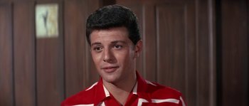 Movie still from “Muscle Beach Party” (1964), directed by William Asher – A man in a red and white striped shirt looks at the camera; Close Up shot, Low angle