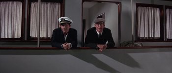 Movie still from “Muscle Beach Party” (1964), directed by William Asher – Two men in suits and hats are sitting in front of a mirror; Medium shot, Low angle