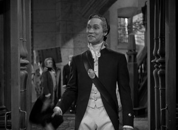 Movie still from “Mutiny on the Bounty” (1935), directed by Frank Lloyd – A black and white photo of a man in a suit; Medium shot, Over the shoulder angle