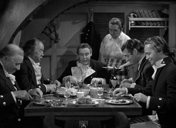 Movie still from “Mutiny on the Bounty” (1935), directed by Frank Lloyd – A black and white photo of people sitting at a dinner table; Medium shot, High angle