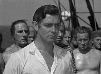 Movie still from “Mutiny on the Bounty” (1935), directed by Frank Lloyd – A black - and - white photo of a man in front of a group of men; Medium shot, Over the shoulder angle