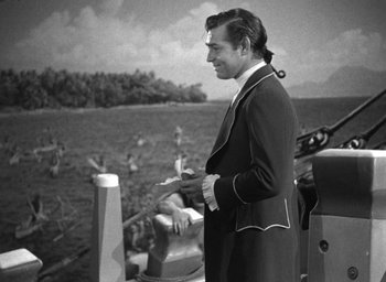 Movie still from “Mutiny on the Bounty” (1935), directed by Frank Lloyd – A black and white photo of a man standing on a boat; Medium shot, High angle