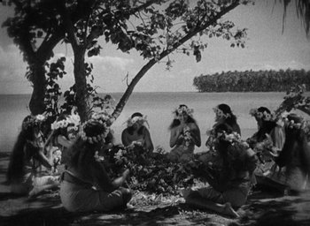 Movie still from “Mutiny on the Bounty” (1935), directed by Frank Lloyd – A black and white photo of a group of women sitting around a tree; Extreme Wide shot, High angle