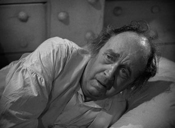 Movie still from “Mutiny on the Bounty” (1935), directed by Frank Lloyd – An older man laying on a bed looking sad; Close Up shot, High angle