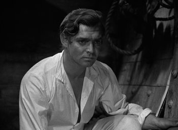 Movie still from “Mutiny on the Bounty” (1935), directed by Frank Lloyd – Black and white photograph of a man sitting on a bench; Close Up shot, Over the shoulder angle