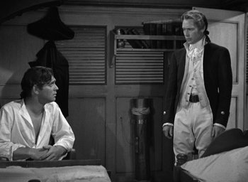 Movie still from “Mutiny on the Bounty” (1935), directed by Frank Lloyd – Two men are sitting at a table in a room; Medium shot, Over the shoulder angle