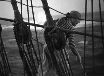 Movie still from “Mutiny on the Bounty” (1935), directed by Frank Lloyd – A man standing on top of a boat in the water; Medium shot, High angle