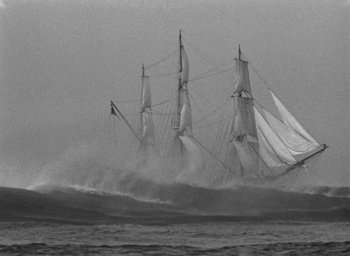 Movie still from “Mutiny on the Bounty” (1935), directed by Frank Lloyd – A large sail boat in the ocean with a large wave behind it; Extreme Wide shot, Low angle