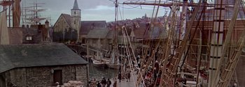 Movie still from “Mutiny on the Bounty” (1962), directed by George Seaton – A group of people standing on a dock next to boats; Extreme Wide shot, High angle