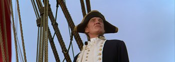 Movie still from “Mutiny on the Bounty” (1962), directed by George Seaton – A man wearing a hat and a uniform on top of a boat; Close Up shot, Low angle