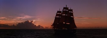 Movie still from “Mutiny on the Bounty” (1962), directed by George Seaton – A large sail boat sailing in the ocean at sunset; Extreme Wide shot, Low angle