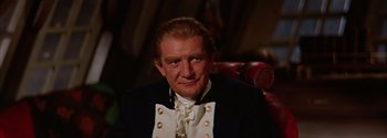 Movie still from “Mutiny on the Bounty” (1962), directed by George Seaton – An older man wearing a suit and tie; Close Up shot, Over the shoulder angle