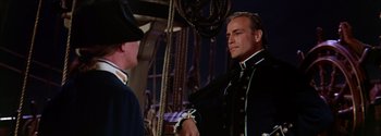 Movie still from “Mutiny on the Bounty” (1962), directed by George Seaton – A man in a uniform standing next to another man; Medium shot, Over the shoulder angle