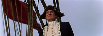 Movie still from “Mutiny on the Bounty” (1962), directed by George Seaton – A man wearing a hat and standing in front of a flag; Close Up shot, Low angle