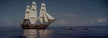 Movie still from “Mutiny on the Bounty” (1962), directed by George Seaton – A large sail boat in the water; Extreme Wide shot, Low angle