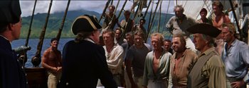 Movie still from “Mutiny on the Bounty” (1962), directed by George Seaton – A group of men standing on top of a boat; Medium shot, Over the shoulder angle