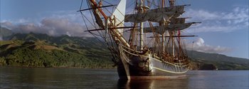Movie still from “Mutiny on the Bounty” (1962), directed by George Seaton – A large sail boat in a body of water; Extreme Wide shot, High angle