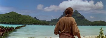 Movie still from “Mutiny on the Bounty” (1962), directed by George Seaton – A man standing on the beach looking out at the ocean; Extreme Wide shot, Over the shoulder angle