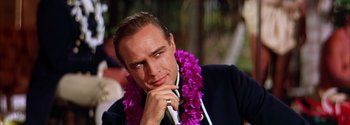 Movie still from “Mutiny on the Bounty” (1962), directed by George Seaton – A person wearing a suit and a lei; Close Up shot, Low angle
