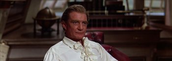 Movie still from “Mutiny on the Bounty” (1962), directed by George Seaton – A person sitting in a chair wearing a white shirt; Close Up shot, High angle