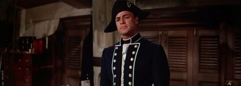 Movie still from “Mutiny on the Bounty” (1962), directed by George Seaton – A man in a military uniform and a hat; Medium shot, Low angle