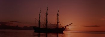 Movie still from “Mutiny on the Bounty” (1962), directed by George Seaton – A large boat floating on top of a body of water; Extreme Wide shot, Low angle