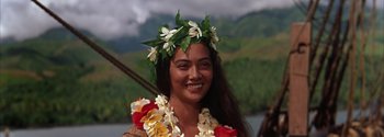 Movie still from “Mutiny on the Bounty” (1962), directed by George Seaton – A woman wearing a lei and a flower crown; Close Up shot, Low angle