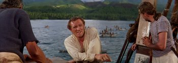Movie still from “Mutiny on the Bounty” (1962), directed by George Seaton – A man leaning on a boat in the middle of a lake; Medium shot, Over the shoulder angle