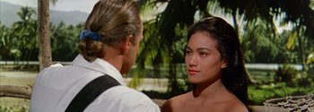 Movie still from “Mutiny on the Bounty” (1962), directed by George Seaton – A man and a woman standing next to each other in front of trees; Close Up shot, Over the shoulder angle
