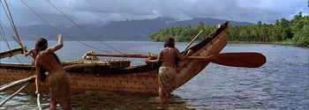 Movie still from “Mutiny on the Bounty” (1962), directed by George Seaton – A man standing on the back end of a wooden boat; Wide shot, High angle