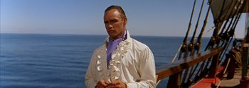Movie still from “Mutiny on the Bounty” (1962), directed by George Seaton – A man wearing a white shirt and a purple shirt; Medium shot, Low angle