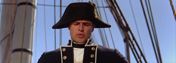 Movie still from “Mutiny on the Bounty” (1962), directed by George Seaton – A person wearing a uniform and a hat; Close Up shot, Low angle