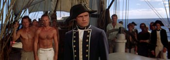 Movie still from “Mutiny on the Bounty” (1962), directed by George Seaton – A man wearing a hat and a uniform; Medium shot, Over the shoulder angle