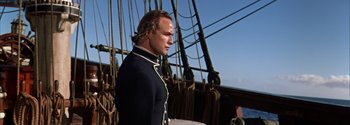 Movie still from “Mutiny on the Bounty” (1962), directed by George Seaton – A man standing on top of a boat in the water; Medium shot, Low angle