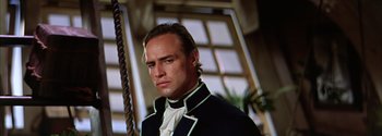 Movie still from “Mutiny on the Bounty” (1962), directed by George Seaton – A person wearing a suit and tie; Close Up shot, Low angle