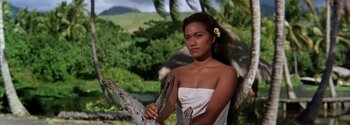 Movie still from “Mutiny on the Bounty” (1962), directed by George Seaton – A beautiful young woman holding a branch in front of trees and bushes; Medium shot, Low angle