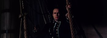 Movie still from “Mutiny on the Bounty” (1962), directed by George Seaton – A man in a uniform standing next to a rope; Medium shot, Low angle