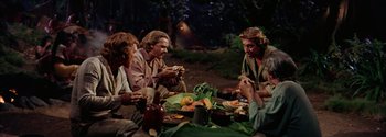 Movie still from “Mutiny on the Bounty” (1962), directed by George Seaton – A group of people sitting around a table eating food; Medium shot, High angle